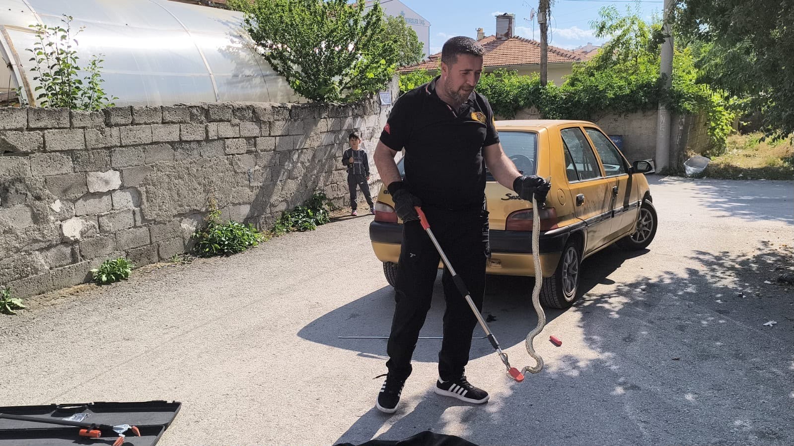 OTOMOBİLİN ALTINA GİREN YILAN İTFAİYE EKİPLERİNCE ÇIKARILDI